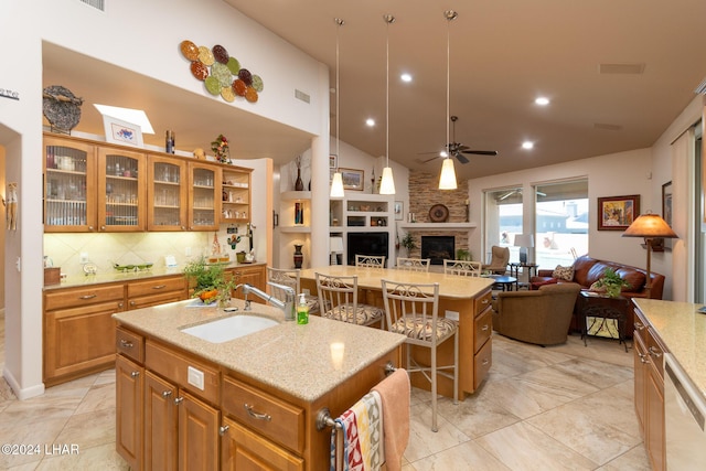 kitchen featuring brown cabinets, open floor plan, a kitchen island with sink, white dishwasher, and a sink