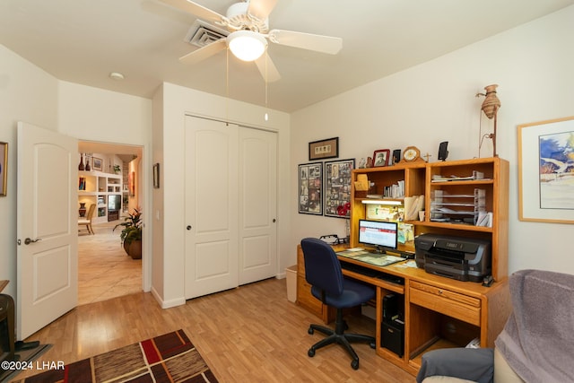 office with light wood-style flooring, visible vents, and a ceiling fan