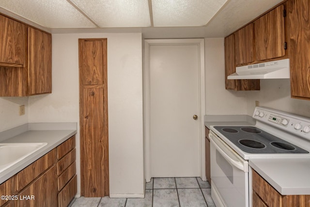 2301 Mcculloch Blvd N Unit E, Lake Havasu City, AZ 86403 - kitchen with electric range, under cabinet range hood, brown cabinetry, and light countertops