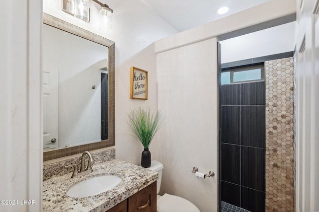 bathroom with vanity, toilet, and a tile shower