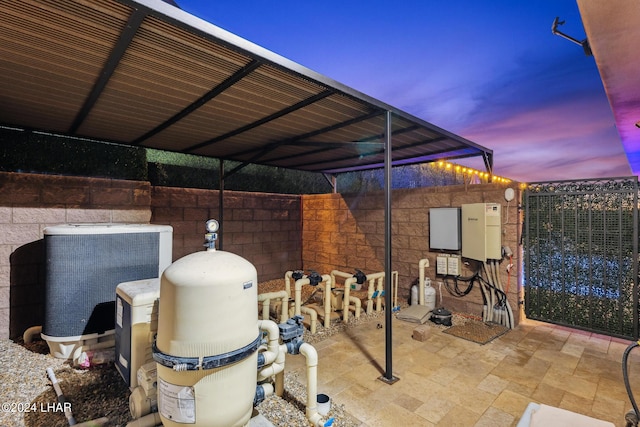 patio terrace at dusk featuring central AC and a carport