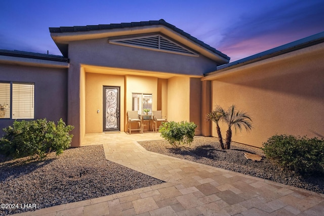 exterior entry at dusk featuring a patio