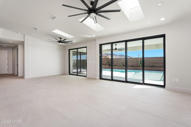 empty room with ceiling fan and a skylight