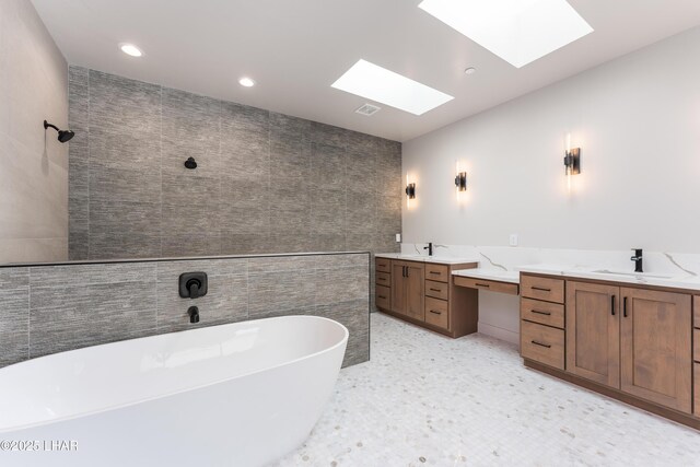 bathroom featuring a tub to relax in, vanity, and tile walls