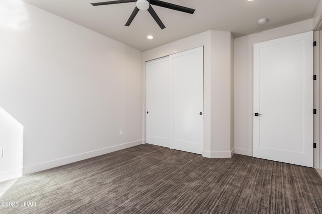 unfurnished bedroom featuring ceiling fan, a closet, and dark colored carpet