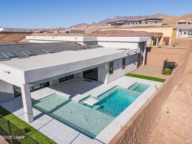 exterior space with a mountain view, a patio, and an in ground hot tub