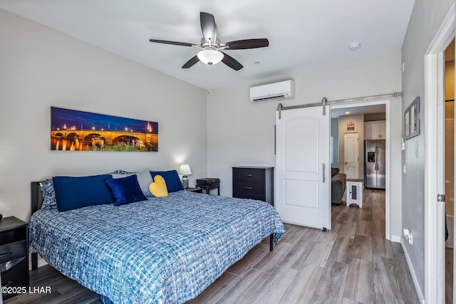 2950 N Kiowa Blvd Unit B102, Lake Havasu City, AZ 86404 - bedroom with stainless steel fridge with ice dispenser, a wall mounted AC, a barn door, and wood finished floors