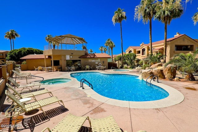 view of pool with a community hot tub, pool water feature, and a patio area