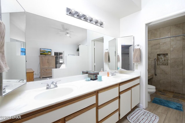 bathroom with hardwood / wood-style floors, a shower with shower door, vanity, ceiling fan, and toilet