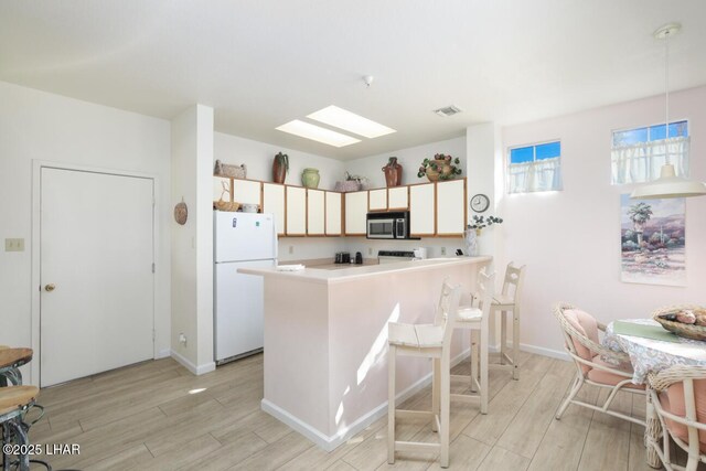 kitchen featuring hanging light fixtures, white fridge, and light hardwood / wood-style flooring