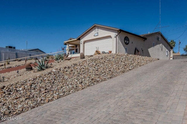 ranch-style home featuring fence, an attached garage, and stucco siding