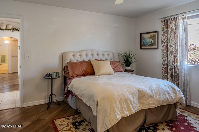 bedroom featuring arched walkways, baseboards, and wood finished floors