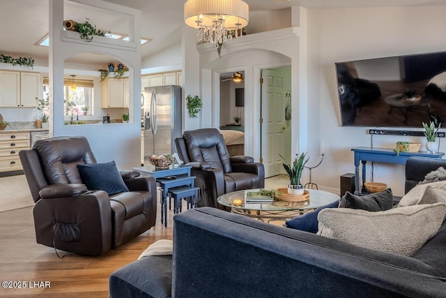 living room featuring a chandelier, arched walkways, and light wood-style flooring