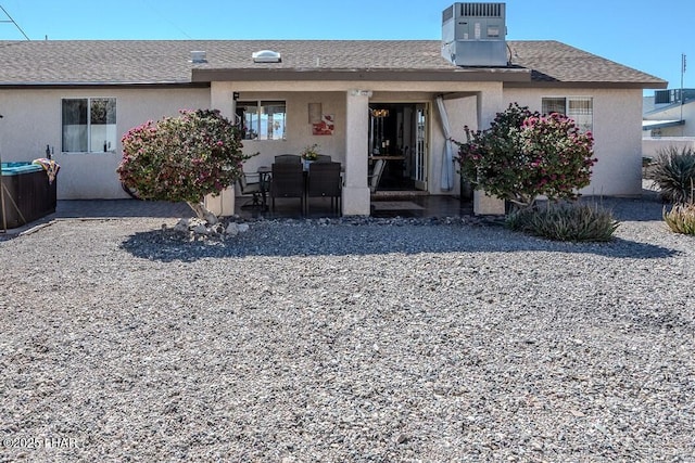 back of house featuring central air condition unit, roof with shingles, a patio, and stucco siding