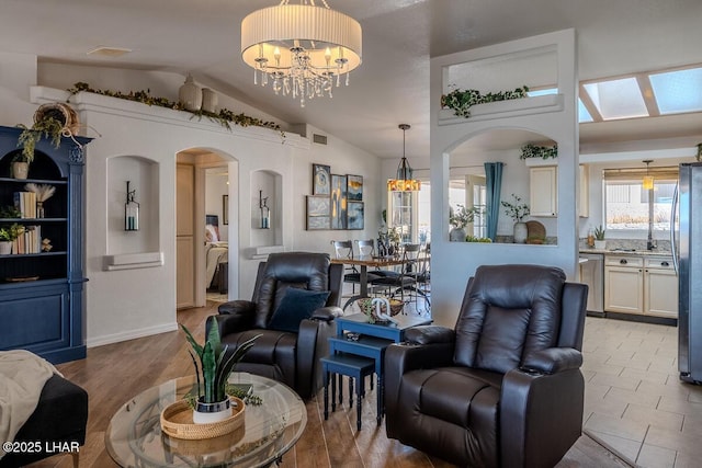 living room featuring arched walkways, vaulted ceiling, visible vents, and a notable chandelier