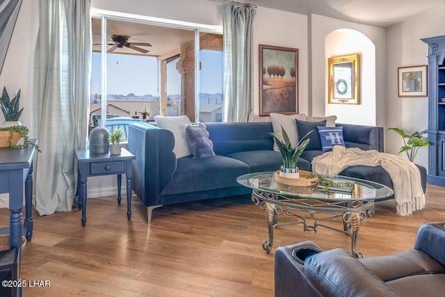 living room with ceiling fan, arched walkways, and wood finished floors