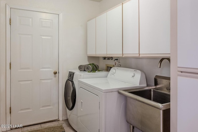 clothes washing area with light tile patterned floors, washing machine and clothes dryer, and cabinet space