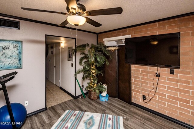 interior space with crown molding, ceiling fan, a textured ceiling, and light hardwood / wood-style flooring