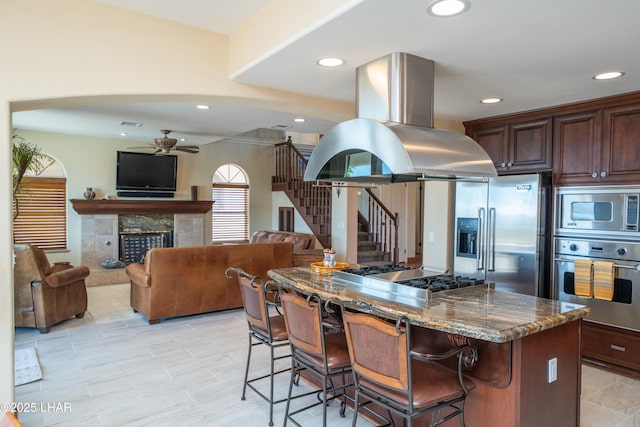 1351 London Bridge Rd Unit 2, Lake Havasu City, AZ 86404 - kitchen featuring appliances with stainless steel finishes, a breakfast bar, dark stone countertops, a ceiling fan, and island exhaust hood