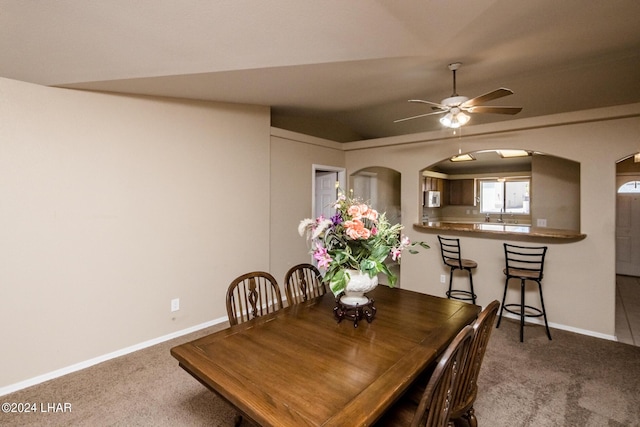 carpeted dining room featuring vaulted ceiling, sink, and ceiling fan