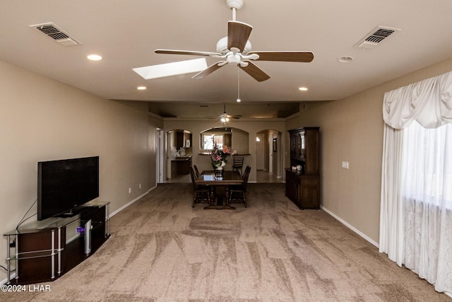 dining room with ceiling fan, a skylight, and carpet floors