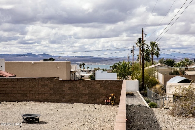 view of water feature with a mountain view, a fire pit, and fence