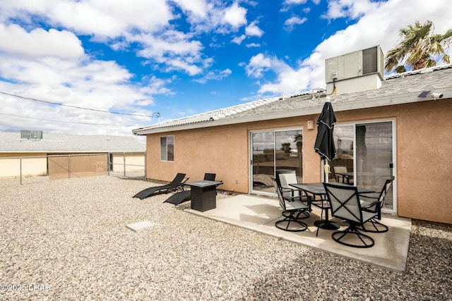 rear view of house with stucco siding, a patio, and fence