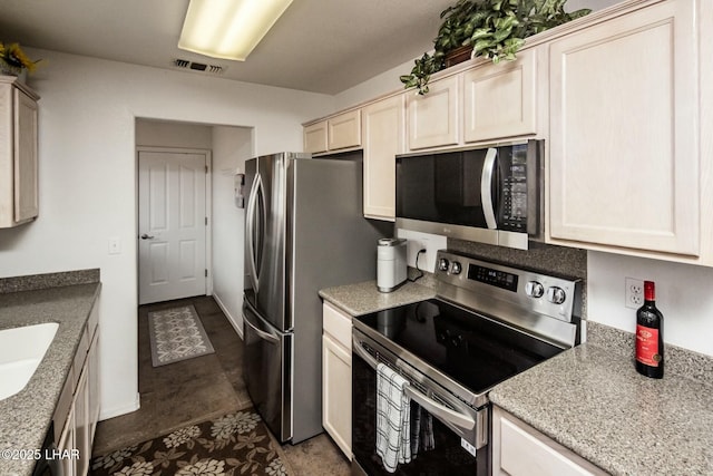 kitchen featuring light stone counters, baseboards, visible vents, a sink, and stainless steel appliances