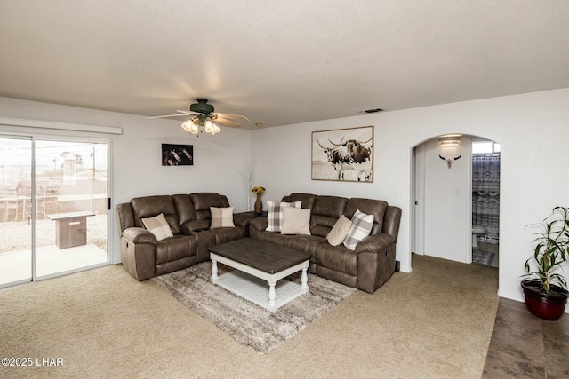 carpeted living area featuring visible vents, arched walkways, and ceiling fan