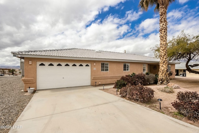 single story home with stucco siding, a garage, driveway, and a tile roof