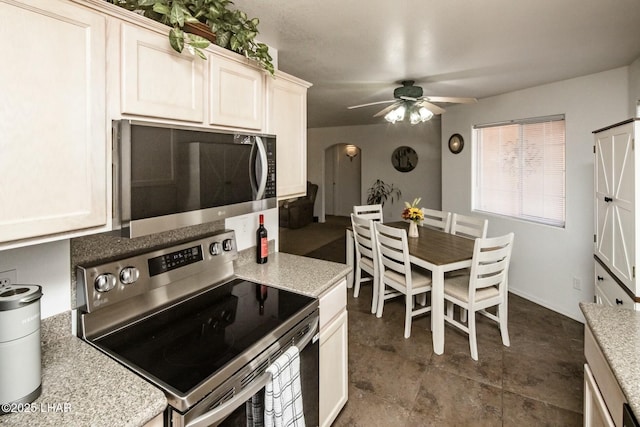 kitchen with stainless steel appliances, arched walkways, a ceiling fan, and light countertops