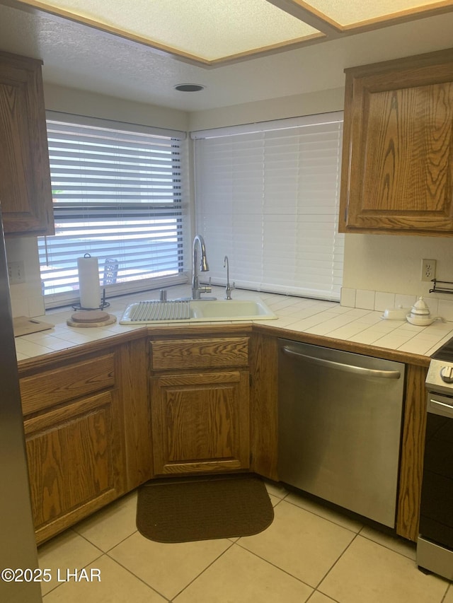 1008 Barcelona Unit 1, Lake Havasu City, AZ 86403 - kitchen with a sink, brown cabinetry, light tile patterned flooring, tile counters, and appliances with stainless steel finishes