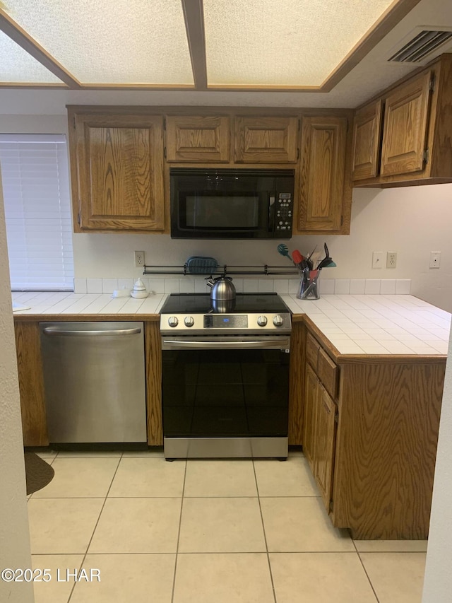 1008 Barcelona Unit 1, Lake Havasu City, AZ 86403 - kitchen with light tile patterned floors, stainless steel appliances, tile countertops, and visible vents