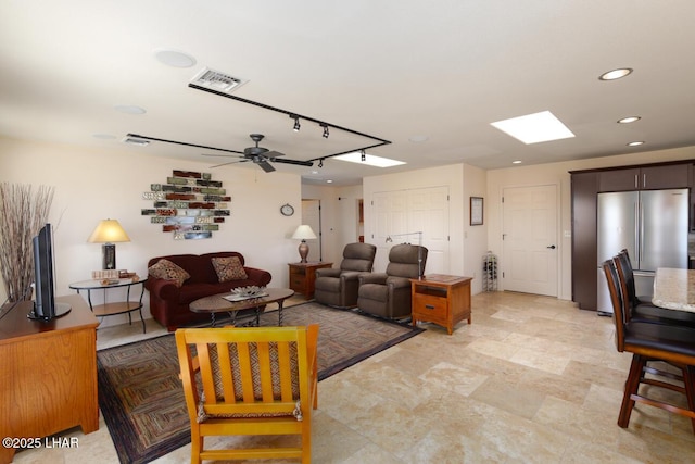 living room with track lighting, ceiling fan, and a skylight