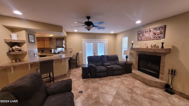 living room featuring french doors, ceiling fan, a tiled fireplace, and sink