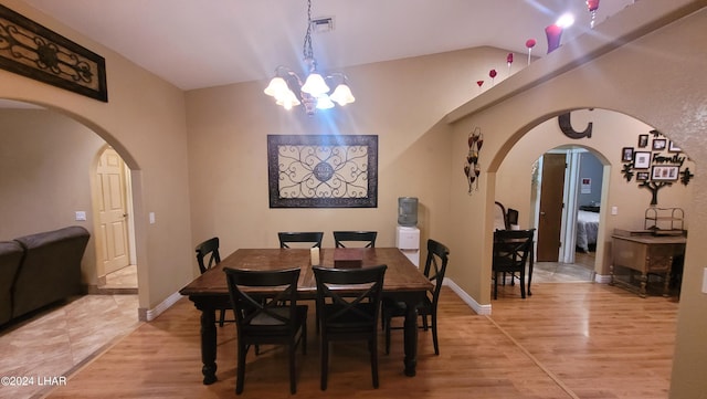 dining space with vaulted ceiling, a chandelier, and light hardwood / wood-style flooring