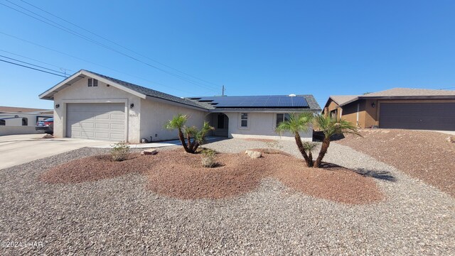 ranch-style home featuring a garage and solar panels