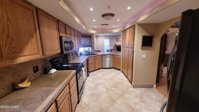 kitchen featuring a raised ceiling, tasteful backsplash, sink, light tile patterned floors, and stainless steel appliances