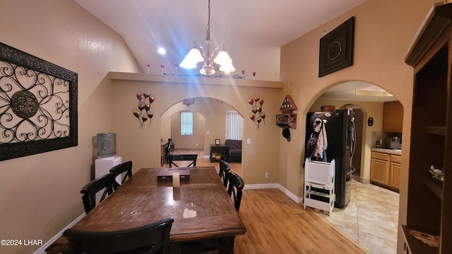 dining area featuring a chandelier, vaulted ceiling, and light hardwood / wood-style flooring