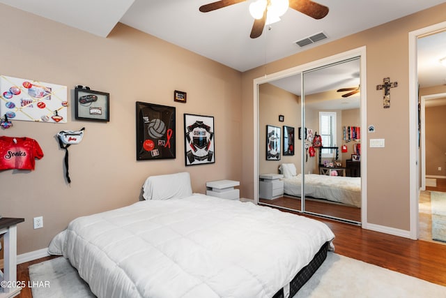 bedroom with baseboards, a closet, visible vents, and wood finished floors