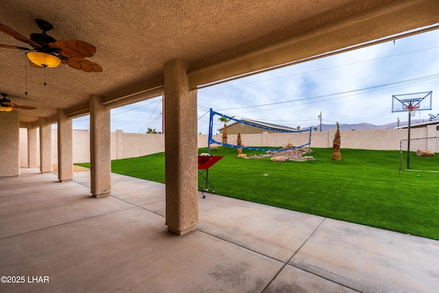 view of patio featuring ceiling fan, fence, and a mountain view