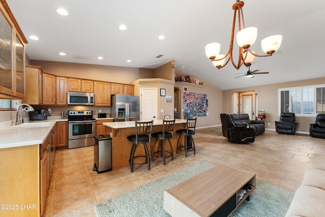 kitchen with light countertops, appliances with stainless steel finishes, a kitchen island, and a sink