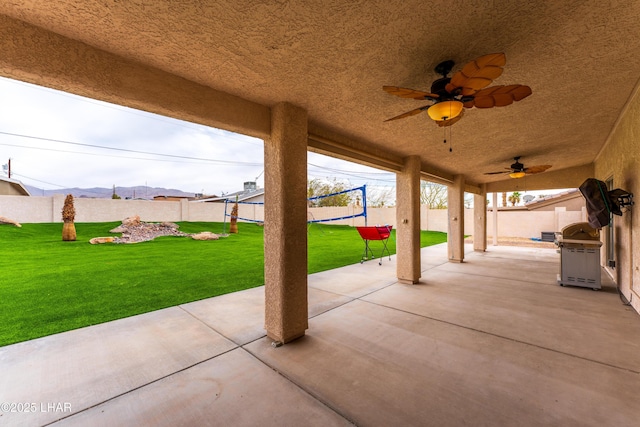 view of patio with a ceiling fan, a mountain view, and fence