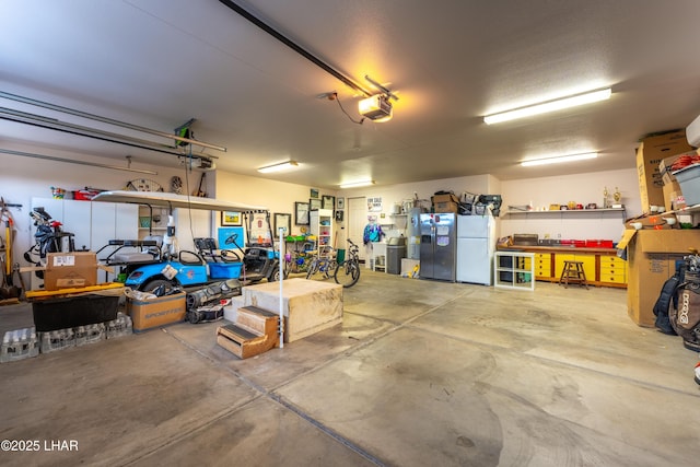 garage featuring stainless steel fridge, freestanding refrigerator, and a garage door opener