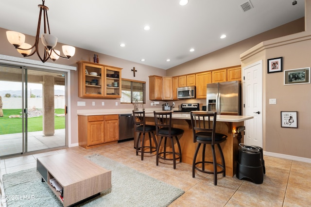 kitchen featuring a center island, light countertops, visible vents, appliances with stainless steel finishes, and glass insert cabinets