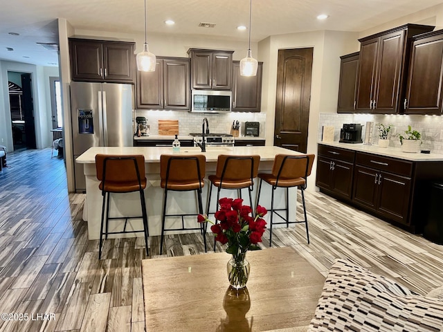 1737 E Alder Cir, Lake Havasu City, AZ 86404 - kitchen featuring stainless steel appliances, light countertops, dark brown cabinetry, a kitchen breakfast bar, and recessed lighting