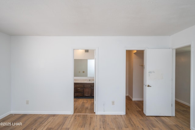 2340 Jamaica Blvd S, Lake Havasu City, AZ 86406 - unfurnished bedroom featuring a spacious closet, wood finished floors, baseboards, and a sink