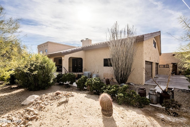 exterior space with a chimney, stucco siding, and central AC