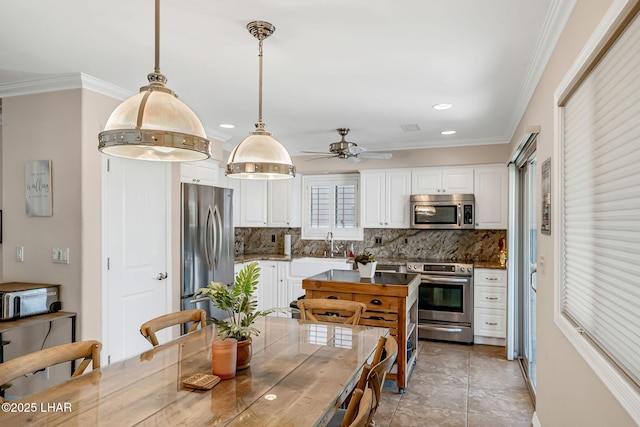 8874 Papago Loop, Parker, AZ 85344 - kitchen with appliances with stainless steel finishes, decorative backsplash, white cabinets, ornamental molding, and ceiling fan