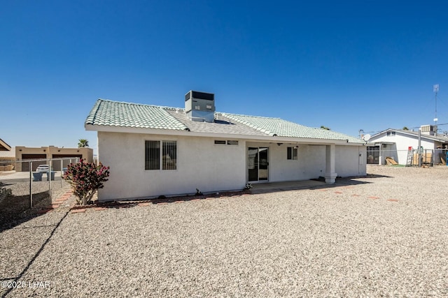 rear view of property with a tiled roof, central AC unit, fence, and stucco siding